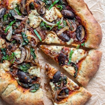 Pizza with large rim topped with cheese, mushroom, onion slices and fresh basil