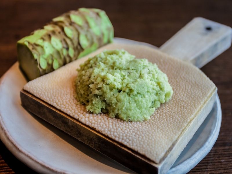 green puree on a small wooden board with a green root behind it