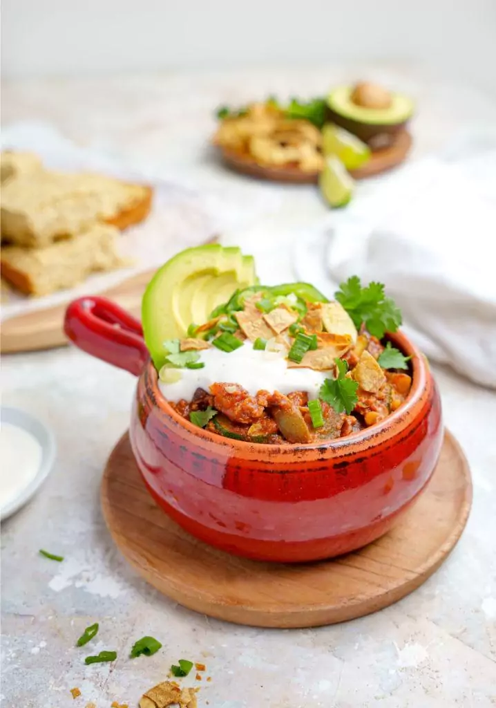 A bowl of TVP chili with sour cream and avocado.
