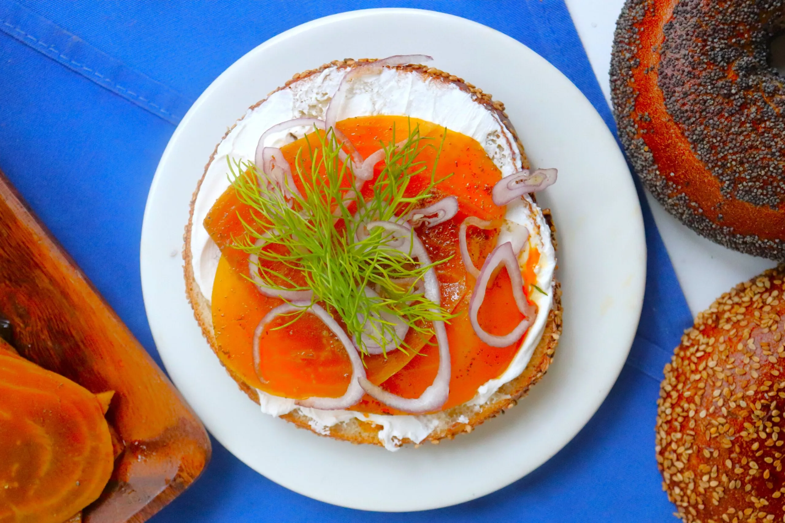 A bagel with a white spread of orange slices of carrots in place of lox.