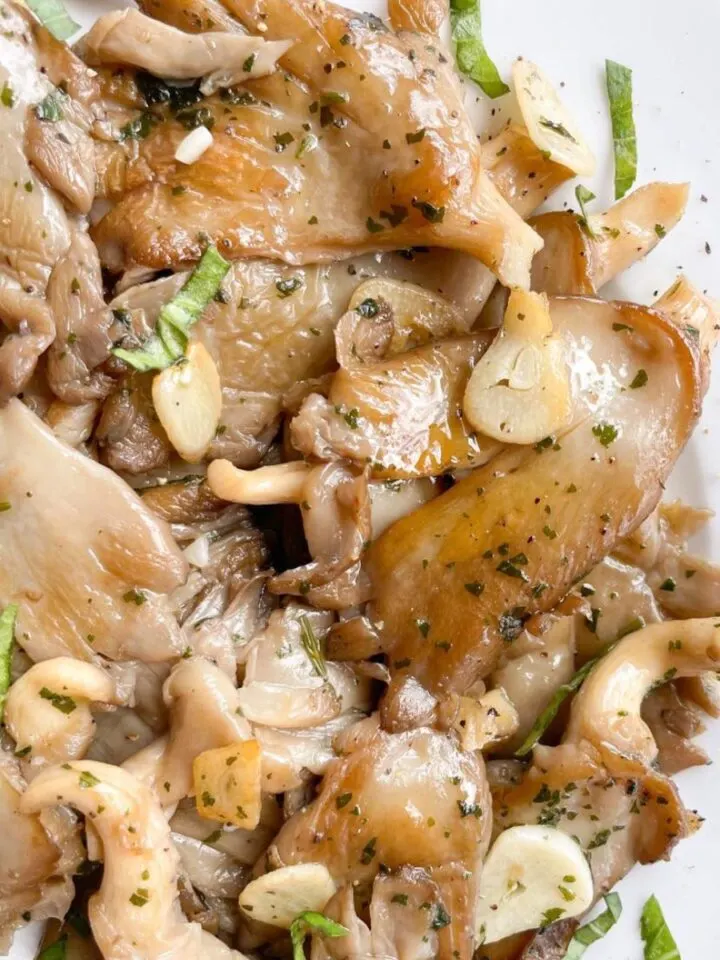 A plate of mushrooms and garlic on a white plate.